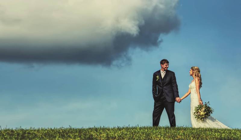 bride and groom walking romantically through a field after their wedding