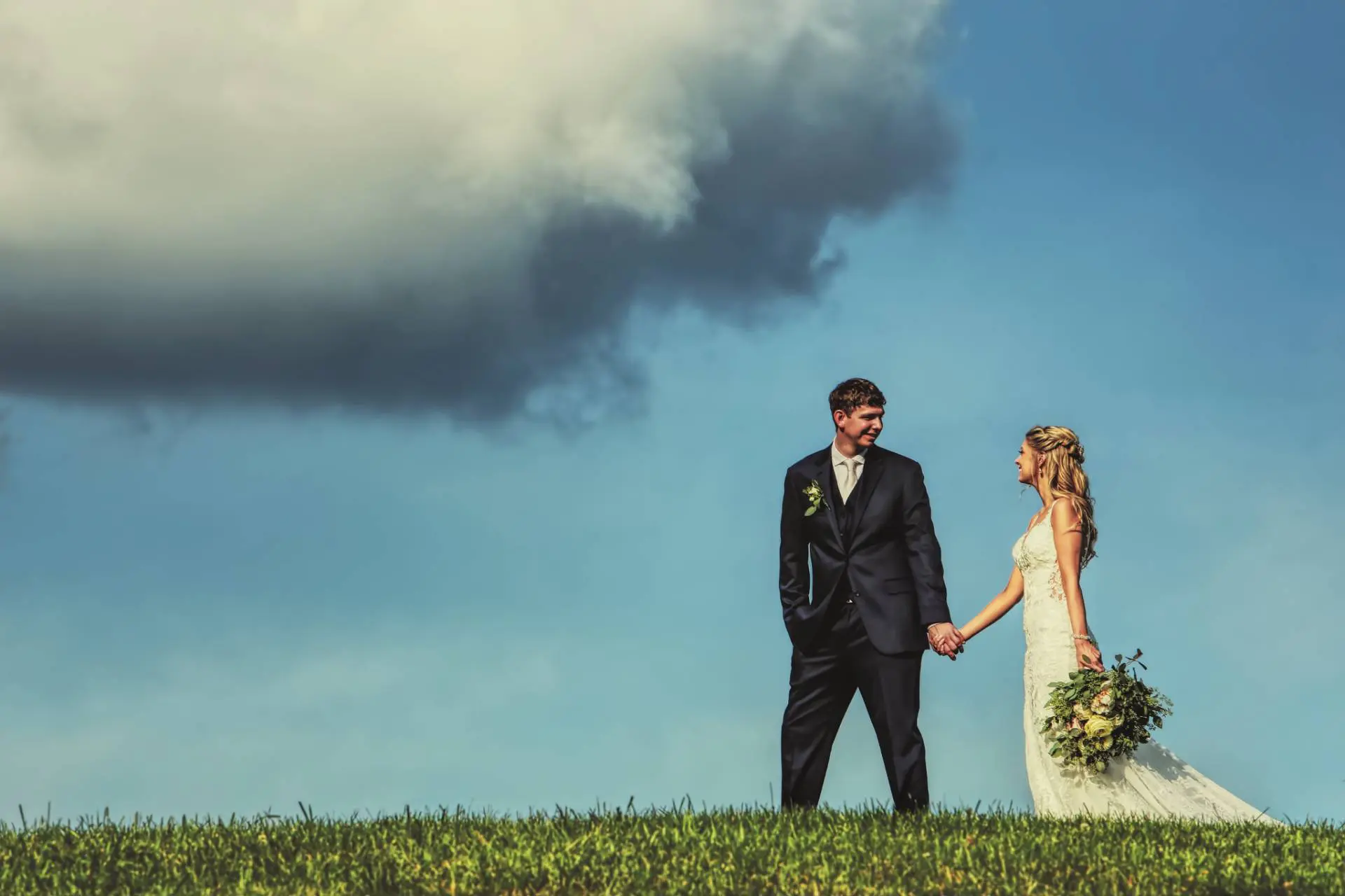 bride and groom walking hand in hand with a dramatic sky
