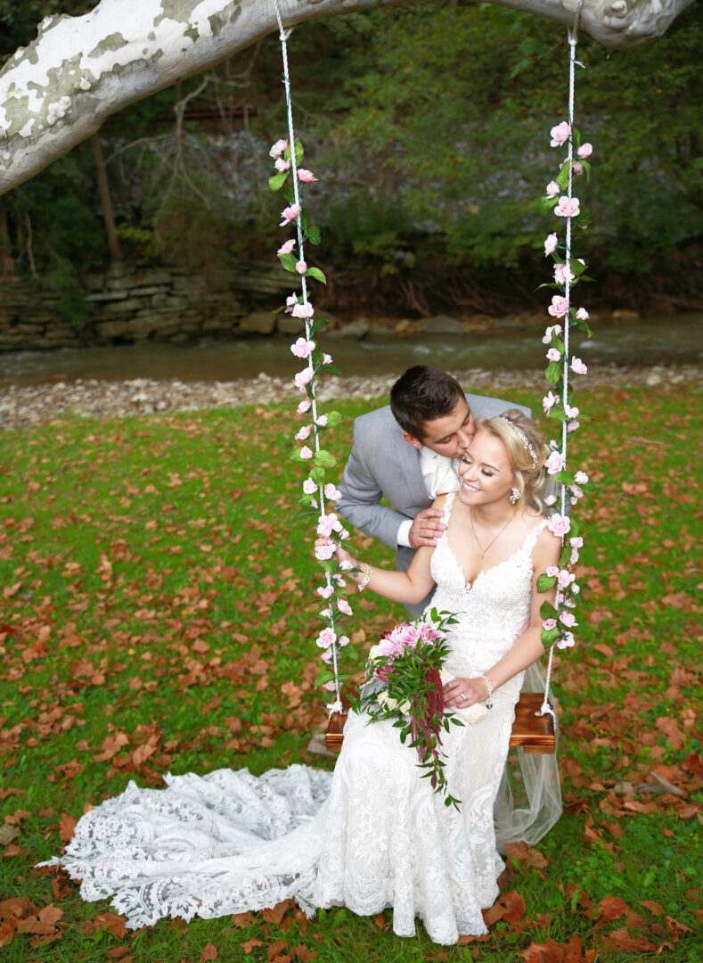 bride sitting on swing as she gets a kiss by the groom at Mingo Creek Park