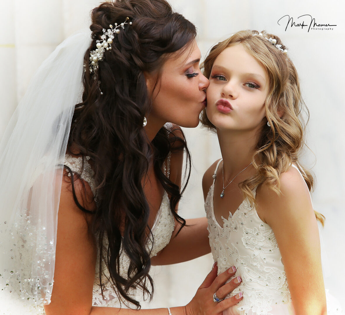Bride kissing her flower girl on the cheek