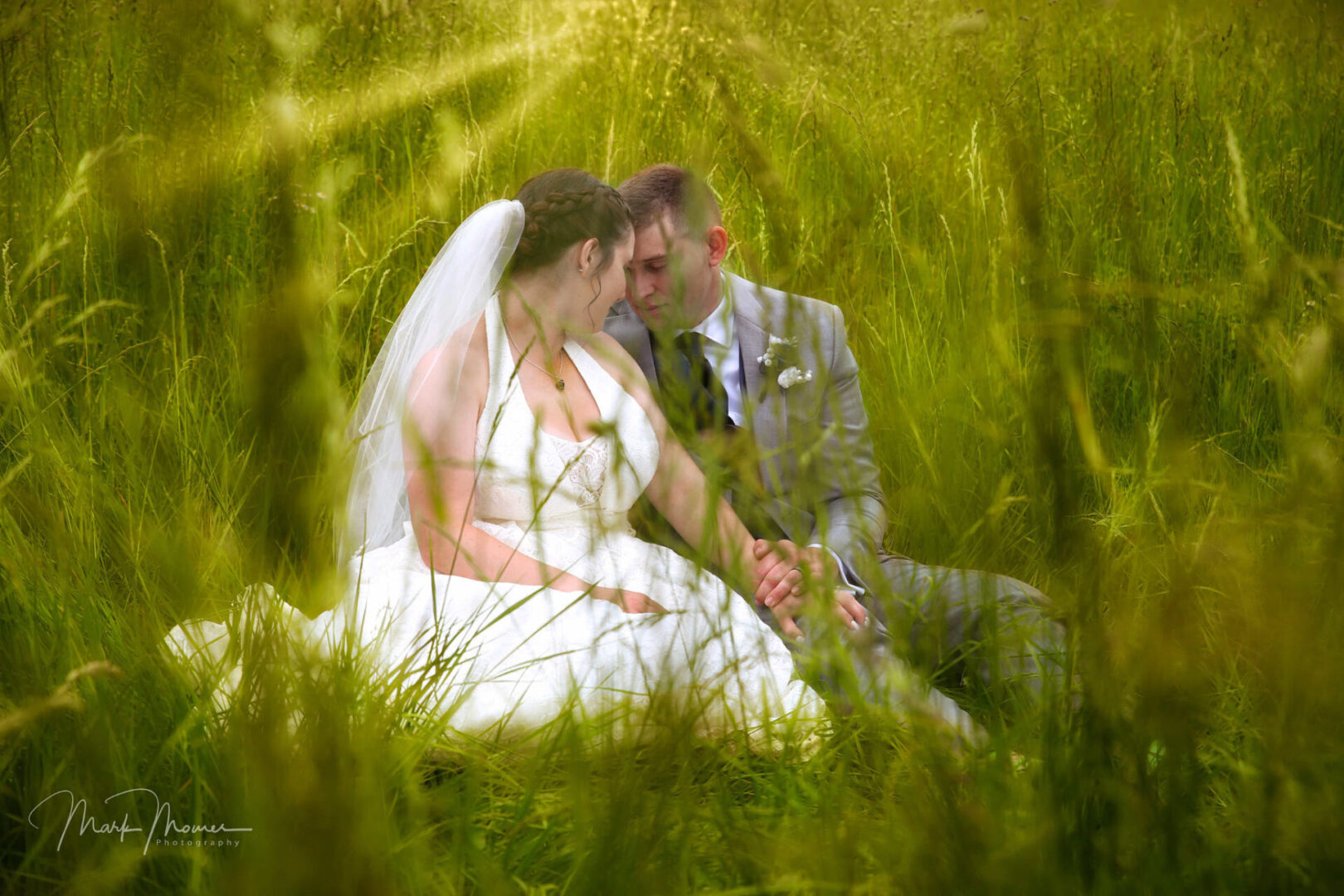 bride and groom sitting in the meadow